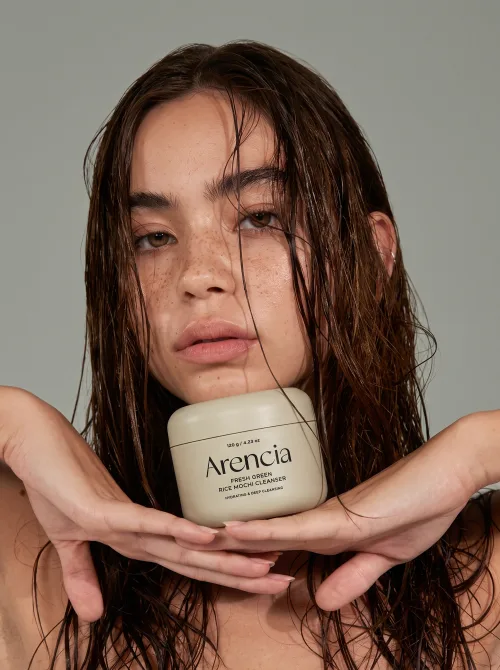 Made on Blogent: beauty campaign, model with wet hair cradling a skincare jar beside her face, soft studio light, clean neutral tones…