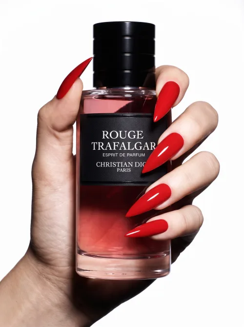 Made on Blogent: luxury product shot, hand with glossy red nails holding a red perfume bottle, seamless white background, crisp studio…